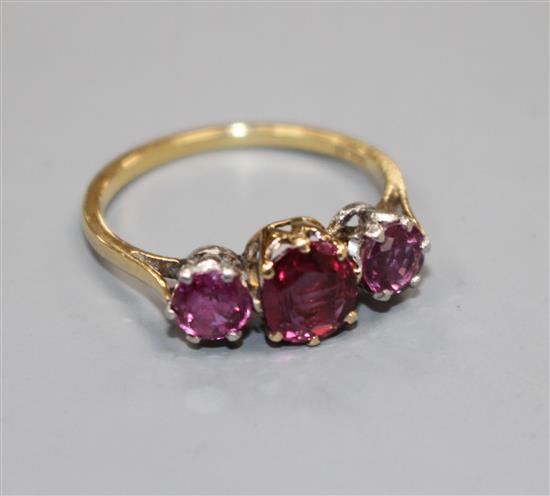 An 18ct and three stone ruby and garnet?? set dress ring, size M, gross 2.7 grams.